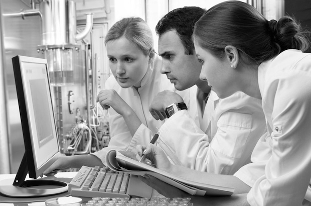 Three lab students intently looking at a computer screen